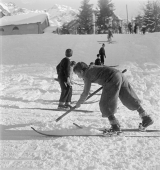 Knabe mit Schaufel am Piste präparieren an einem Hang mit Kinder auf Skiern