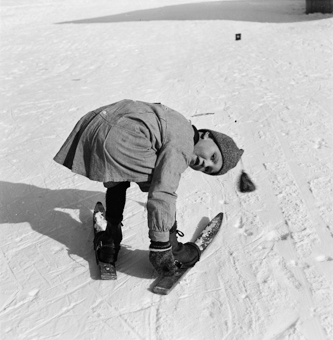 Kind beim Anschnallen von Fassdauben (kurzen Skis)