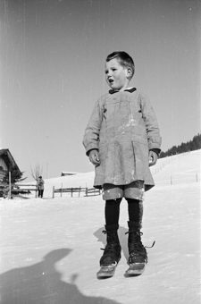 Bauernkind mit Fassdauben (kurzen Skis) an einem Schneehang