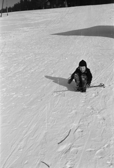 Mädchen mit Skistöcken im Schnee sitzend