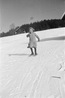 Kind mit Fassdauben (kurzen Skis) fährt einen Hang hinunter