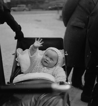 Winkendes Kleinkind in Kinderwagen sitzend