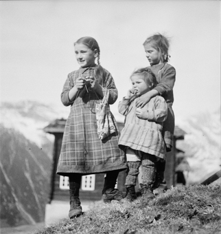 Drei Bauernmädchen in ländlicher Umgebung, eines mit Strickzeug