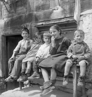 Lachende Kinder auf einer Bank vor Bauernhaus