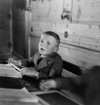 Verträumter Knabe mit Schiefertafel und Buch