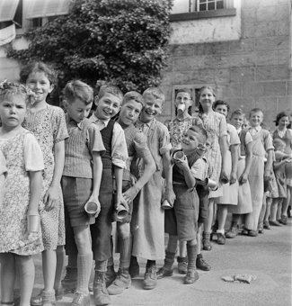 Schulkinder mit Bechern beim Anstehen für Essen oder Trinken