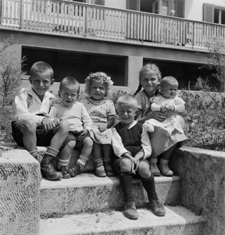 Kinder auf einer Treppe sitzend vor Wohnhaus