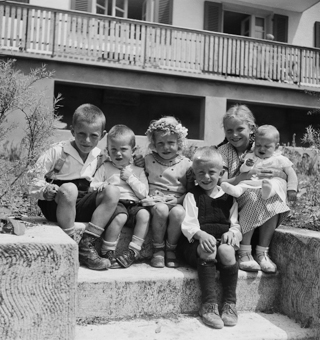 Kinder auf einer Treppe sitzend vor Wohnhaus