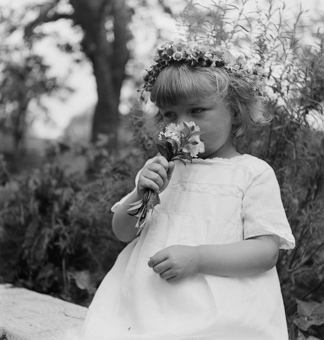 Kleines Mädchen in weissem Sommerkleid mit Blumenkranz und Blumensträusschen