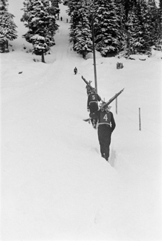 Skispringer mit geschulterten Skis am Hochlaufen zur Sprungschanze