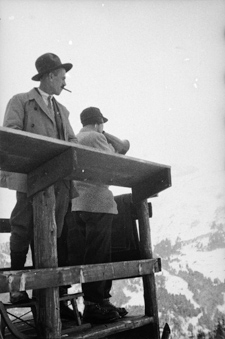 Frau mit Megaphon an Skispringen auf Holzturm stehend