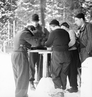 Frauen und Männer am Skispringen um einem Tisch stehend