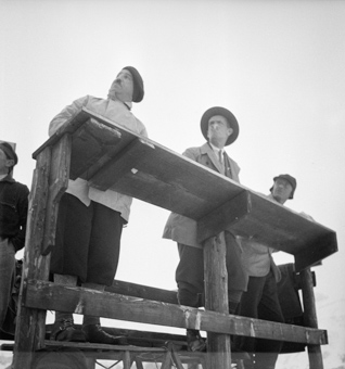 Punkterichter von Skispringen auf Holzturm den Hang hochblickend