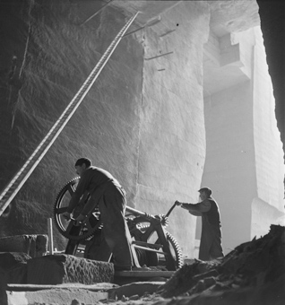 Zwei Arbeiter beim Brechen von Sandstein mit einem «Steinbrecher» (Zerkleinerungsmaschine) im Innern des Steinbruchs