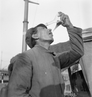 Bahnarbeiter trinkt aus einem Porron