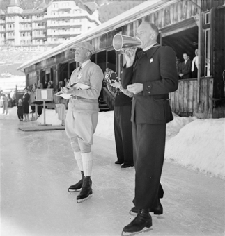 Hinten ein Fotograf, eine Zuschauertribüne und das Hotel Victoria-Lauberhorn