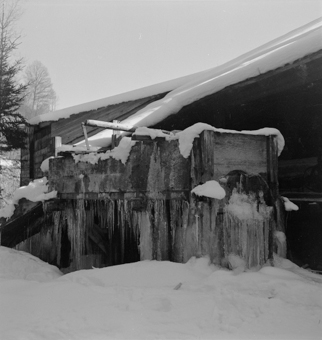 Eiszapfen an Brunnentrog neben Bauernhaus