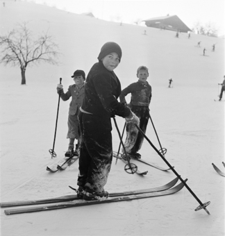 Drei Kinder auf Skiern an einem Schneehang