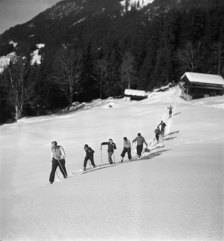 Lehrer mit Schülern auf Skiern beim Aufstieg an Schneehang