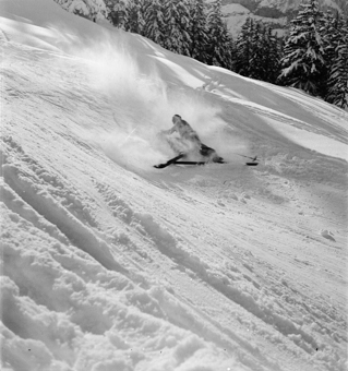 Skifahrer in stiebendem Schnee an Steilhang