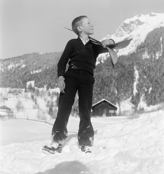 Knabe mit geschulterten Skis