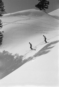 Zwei Skifahrer bei der Abfahrt durch den Tiefschnee
