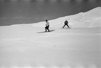 Zwei Skifahrer auf der Piste, der eine im Stemmbogen