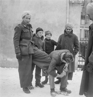 Spahis (Internierte) mit Kindern beim Montieren von Schlittschuhen