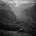 Bergbauer auf einer steilen Alpwiese beim Heurechen